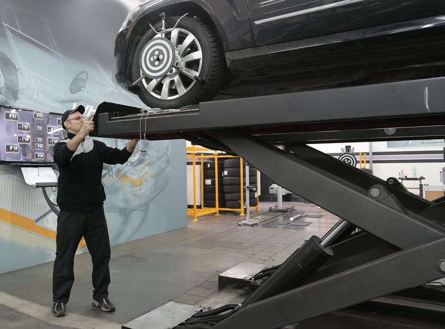 Mechanic carefully examining car on hydraulic lift in automotive workshop, ensuring safety and performance.