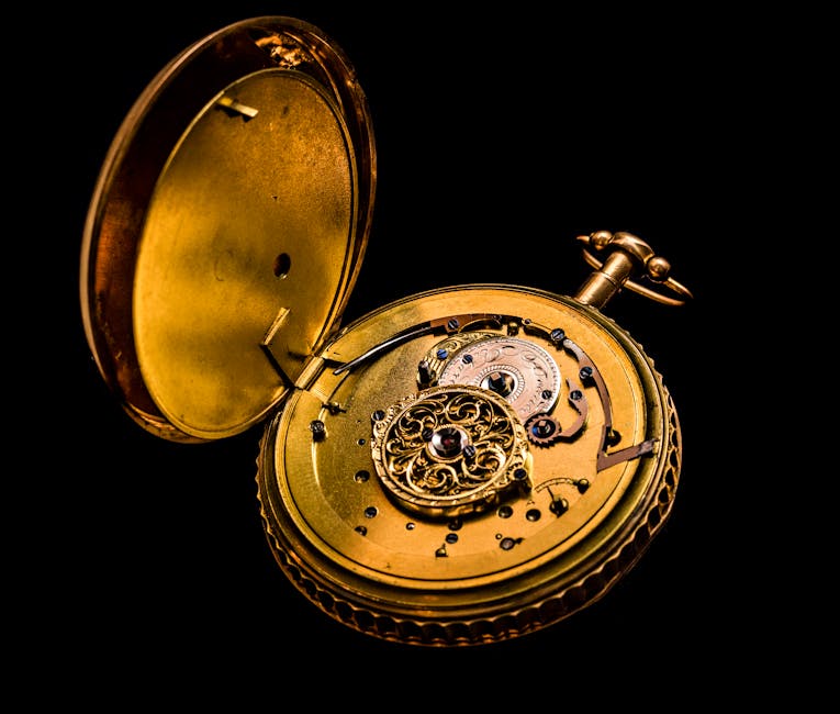 Detailed photograph of a vintage gold pocket watch showing intricate mechanics on a black background.